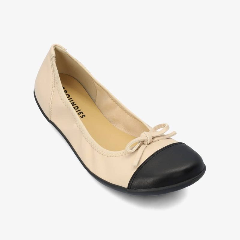 Beige & Black Groundies Ruby leather ballet flat. Shoes are light beige with a leather bow, black leather toe cap, black soles, and elastic around the openiing. Right shoe is shown here diagonally to the right against a white background. #color_beige-black