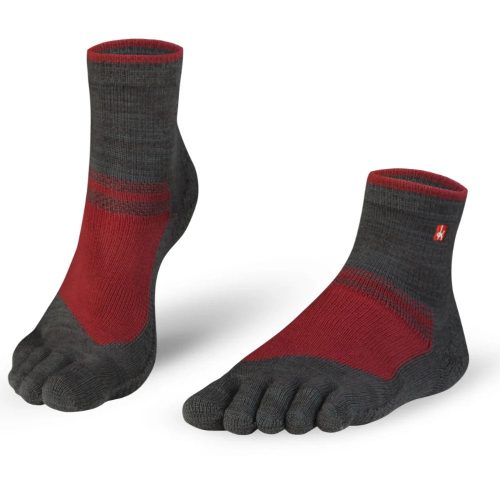 A pair of grey and red Knitido outdoor midi toe socks. Socks are a dark heathered grey is dark with red at the top of the foot and top of the ankle opening. Both socks are shown facing diagonally left with the left sock heel up against a white background. #color_grey-red