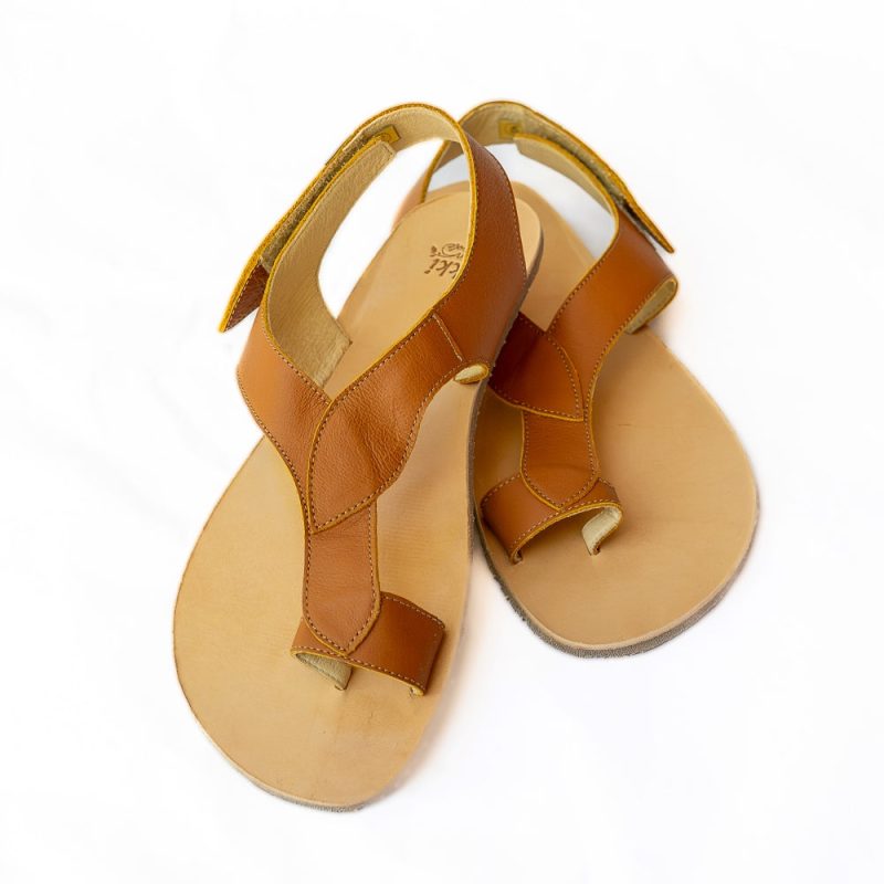 A photo of light brown Tikki Soul leather sandals with a tan sole and footbed. Three leaf-shaped straps connect starting at a toe ring, surrounding the back of the foot and coneecting to a velcro closure at the outside of the ankle. Both shoes are shown here from the front with the left shoe heel resting on the right against a white background. #color_sahara-leather